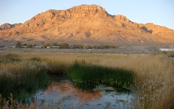Photo of desert, mountains, houses, and a small body of water